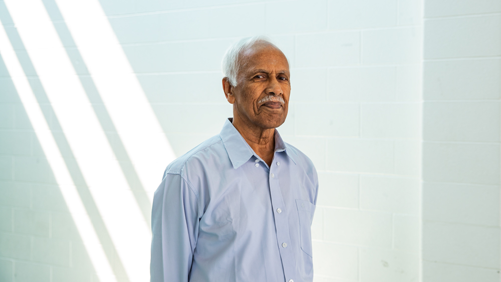 Arumugam poses in front of a beam of light.