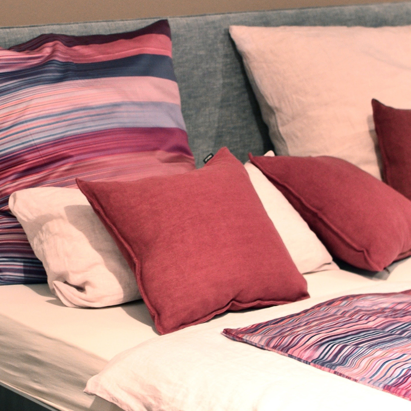 Mixed pattern pillows on white bedding.