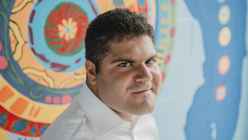 Domenic poses for the camera in front of a brightly coloured mural 